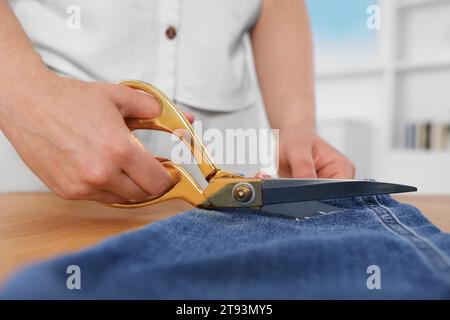 Frau macht zerrissene Jeans am Tisch, Nahaufnahme Stockfoto