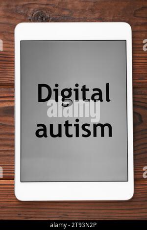 Tablet mit Phrase Digital Autism auf Holztisch, Draufsicht. Suchtverhalten Stockfoto