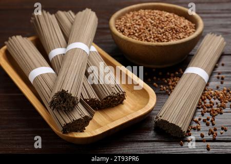 Ungekochte Buchweizennudeln (Soba) und Körner auf Holztisch, Nahaufnahme Stockfoto