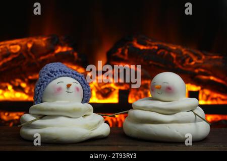 Niedliche dekorative Schneemänner auf Holzboden in der Nähe des Kamins Stockfoto