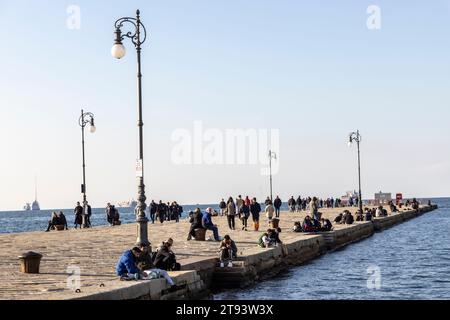 TRIEST, ITALIEN – 19. November 2023: Menschen am Molo Audace Pier von Triest an einem wunderschönen Herbsttag Stockfoto