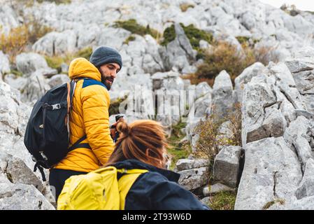 Mann und Frau klettern einen Berg zwischen den Felsen. Ein paar Wanderungen in den hohen Bergen. Outdoor-Sport und gesunder Lebensstil. Stockfoto