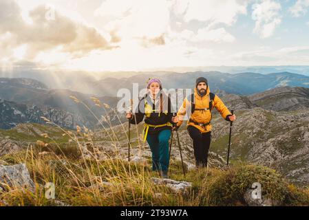 Zwei Wanderer wandern in den Bergen. Ein paar Bergsteiger, die einen Berg hinaufsteigen. Sport und körperliche Aktivität in der Natur. Stockfoto