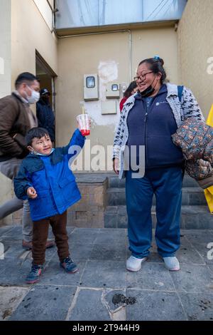 Viacha, La Paz, Bolivien – 16. August 2022: Bolivianische Frauen und ein Junge mit Masken hängen auf der Straße und trinken Saft Stockfoto