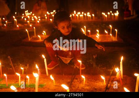 Christen beten neben den Gräbern ihrer Familienmitglieder auf einem Friedhof während des „All Souls Day“ am Stadtrand von Agartala. Tripura, Indien. Stockfoto