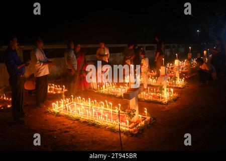 Christen beten neben den Gräbern ihrer Familienmitglieder auf einem Friedhof während des „All Souls Day“ am Stadtrand von Agartala. Tripura, Indien. Stockfoto