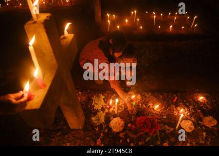 Christen beten neben den Gräbern ihrer Familienmitglieder auf einem Friedhof während des „All Souls Day“ am Stadtrand von Agartala. Tripura, Indien. Stockfoto