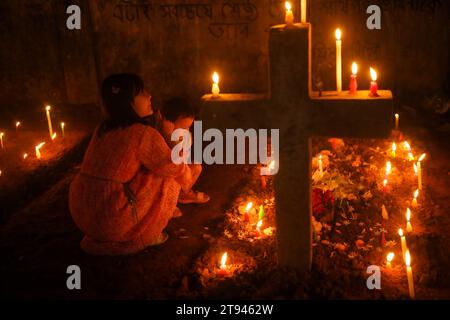 Christen beten neben den Gräbern ihrer Familienmitglieder auf einem Friedhof während des „All Souls Day“ am Stadtrand von Agartala. Tripura, Indien. Stockfoto