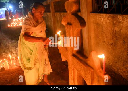 Christen beten neben den Gräbern ihrer Familienmitglieder auf einem Friedhof während des „All Souls Day“ am Stadtrand von Agartala. Tripura, Indien. Stockfoto