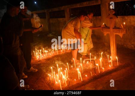 Christen beten neben den Gräbern ihrer Familienmitglieder auf einem Friedhof während des „All Souls Day“ am Stadtrand von Agartala. Tripura, Indien. Stockfoto