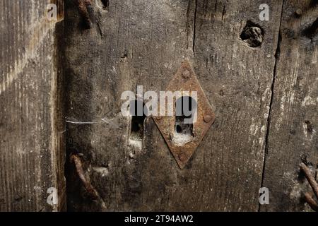 Schlüsselloch aus Metall mit Diamant an verwitterter Holztür im Kloster Raca, Serbien Stockfoto