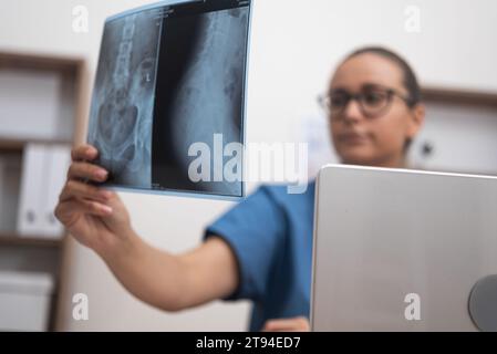 Die Ärztin analysiert die Ergebnisse des Röntgenfilms des Patienten auf ihrem Laptop. Stockfoto