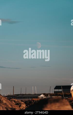 Vollmond bei Sonnenuntergang über der Stadt Oostende an der Westküste Belgiens. Ein kosmisches Objekt in seiner vollen Pracht. Stockfoto