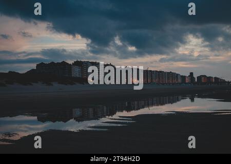 Sonnenuntergang an den Sandstränden von Oostende, Westbelgien. Die letzten Sonnenstrahlen brechen durch die Wolken. Rot-orange Hölle. Stockfoto