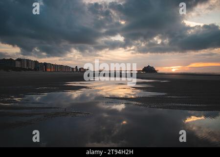 Sonnenuntergang an den Sandstränden von Oostende, Westbelgien. Die letzten Sonnenstrahlen brechen durch die Wolken. Rot-orange Hölle. Stockfoto