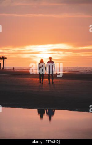 Romantischer Spaziergang eines jungen Paares an den Stränden von Oostende im Westen Belgiens bei Sonnenuntergang. Liebe und Hingabe. Reflexion in einem Wasserbecken. Stockfoto