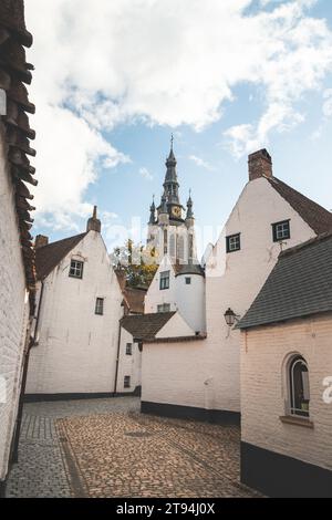 Historisches Zentrum von Begijnhof in Kortrijk mit dem Glockenturm von Courtrai im Hintergrund. Eine Sammlung von Einzelhäusern und/oder Gemeinschaftshäusern, Häusern und Stockfoto