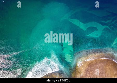 Dieses Bild zeigt eine malerische Strandszene mit einem ruhigen Körper aus blauem Wasser, umgeben von großen Felsen, Baja Beach Stockfoto