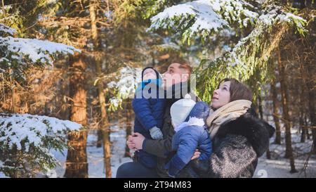 Eine glückliche Familie schaut sich die Bäume in den Winterwäldern an. Stockfoto