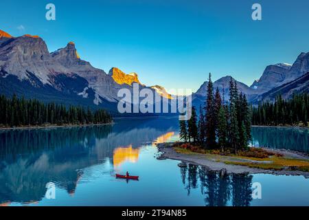 Ein Kanu liegt auf einem ruhigen Bergsee, umgeben von majestätischen schneebedeckten Bergen und üppigen Kiefern, Morine Lake Canada Stockfoto