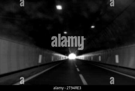 Absichtlich verschwommener Straßentunnel ohne Autos und Sie sehen das Licht in der Ferne in Schwarz-weiß Stockfoto