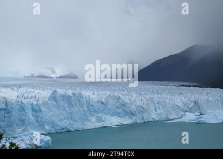 Blick auf den Perito Moreno Gletscher (Patagonien, Argentinien) vom Fußweg auf der anderen Seite, wo Touristen spazieren gehen. Stockfoto