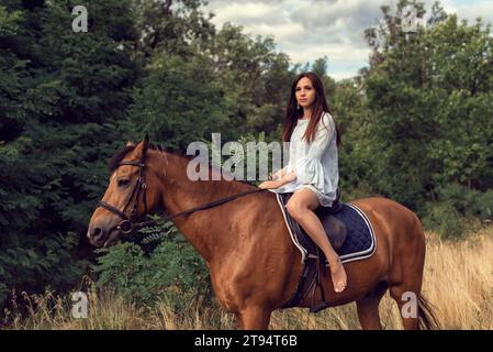 Mädchen auf einem Feld auf einem braunen Pferd Stockfoto