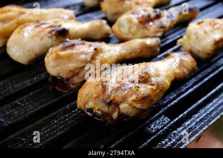 Gegrillte Hähnchenkeulen auf einem Grill, mit verkohlten Grillspuren, saftig und gut gewürzt, perfekt zum Essen im Freien Stockfoto