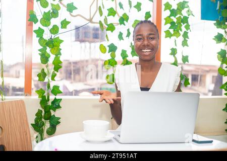 Stilvolle Frau, die am Laptop arbeitet, ein strahlendes Lächeln, sie mühelos Multitasking auf ihrem Laptop Stockfoto