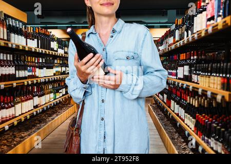 Weibliche Konsumentin, die den Wein im Spirituosenladen kauft. Stockfoto