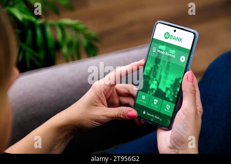 Mobile Banking-Anwendung auf dem Telefonbildschirm. Frau, die ein Smartphone hält und die Home-Banking-App öffnet. Stockfoto