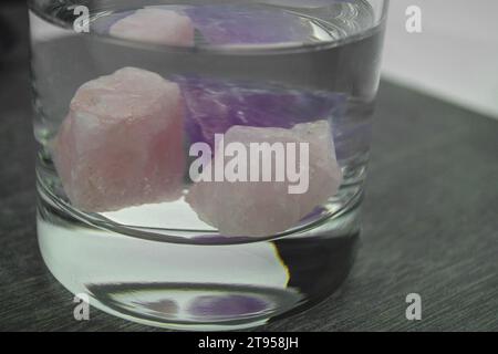 Rosenquarz und Amethyst in einem Glas Wasser Stockfoto