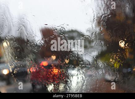 Der Verkehr wird durch eine regenbedeckte Windschutzscheibe betrachtet Stockfoto