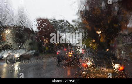 Der Verkehr wird durch eine regenbedeckte Windschutzscheibe betrachtet Stockfoto