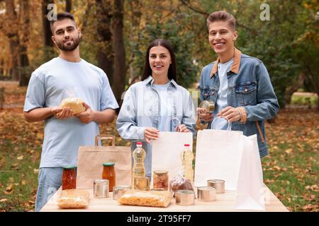 Porträt von Freiwilligen, die Lebensmittel am Tisch im Park packen Stockfoto