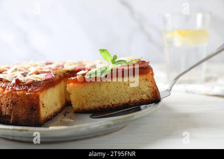 Ein Stück frisch gebackener Rhabarberkuchen mit Mandelflocken auf weißem Holztisch, Nahaufnahme Stockfoto