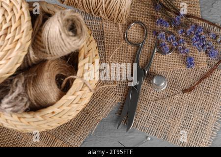 Stücke Sackleinen und Nähwerkzeuge auf grauem Holztisch, flach gelegt Stockfoto