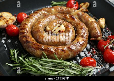 Köstliche hausgemachte Wurst mit Knoblauch, Tomaten, Rosmarin und Gewürzen in der Grillpfanne, Nahaufnahme Stockfoto