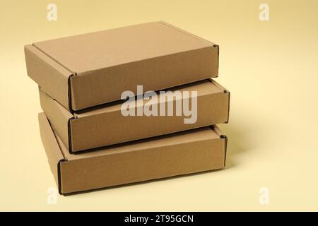 Stapel geschlossener Kartonschachteln auf blassgelbem Hintergrund Stockfoto