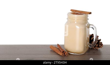 Köstlicher Eierlikör und Zimtstangen auf Holztisch vor weißem Hintergrund. Leerzeichen für Text Stockfoto