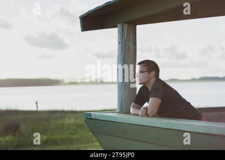 Person, die aus dem Fenster einer Hütte schaut Stockfoto