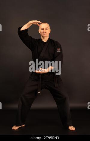 Porträt des Aikido-Sensei-Meisters mit schwarzem Sensei-Gürtel in Taekwondo-Kimono auf schwarzem Hintergrund. Traditioneller Samurai-Hakama-Kimono. Gesunder Lebensstil Stockfoto