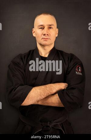 Porträt des Aikido-Sensei-Meisters mit schwarzem Sensei-Gürtel in Taekwondo-Kimono auf schwarzem Hintergrund. Traditioneller Samurai-Hakama-Kimono. Gesunder Lebensstil Stockfoto