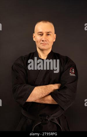 Porträt des Aikido-Sensei-Meisters mit schwarzem Sensei-Gürtel in Taekwondo-Kimono auf schwarzem Hintergrund. Traditioneller Samurai-Hakama-Kimono. Gesunder Lebensstil Stockfoto