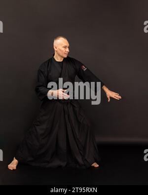 Porträt des Aikido-Sensei-Meisters mit schwarzem Sensei-Gürtel in Taekwondo-Kimono auf schwarzem Hintergrund. Traditioneller Samurai-Hakama-Kimono. Gesunder Lebensstil Stockfoto