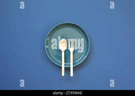 Leere Tellerschale mit Löffel, Gabel auf marineblauem Hintergrund. Draufsicht Stockfoto