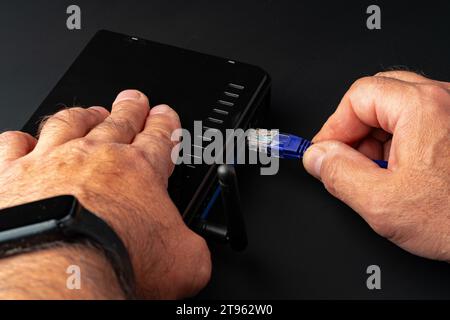 Die Hand des Mannes verbindet das Internetkabel mit dem wlan-Router Stockfoto