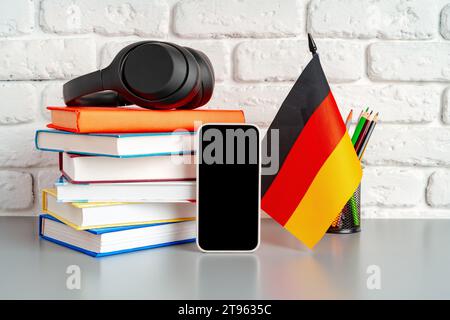 Stapel Bücher und Flagge Deutschlands auf dem Schreibtisch. Deutschsprachenlernkonzept Stockfoto