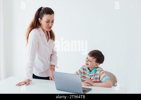 Lehrerin, die dem Jungen beibringt, Computer zu benutzen Stockfoto