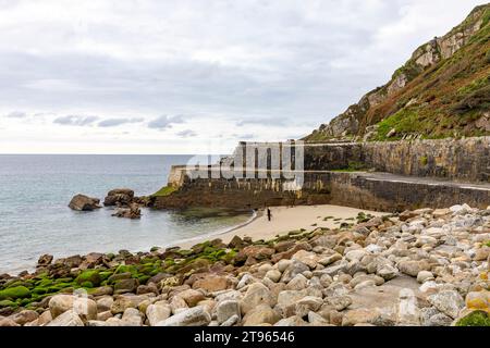 Lamorna Cove, zwei Leute gehen mit ihrem Hund am Sandstrand, Cornwall Südwesten Englands, Großbritannien, 2023 Stockfoto